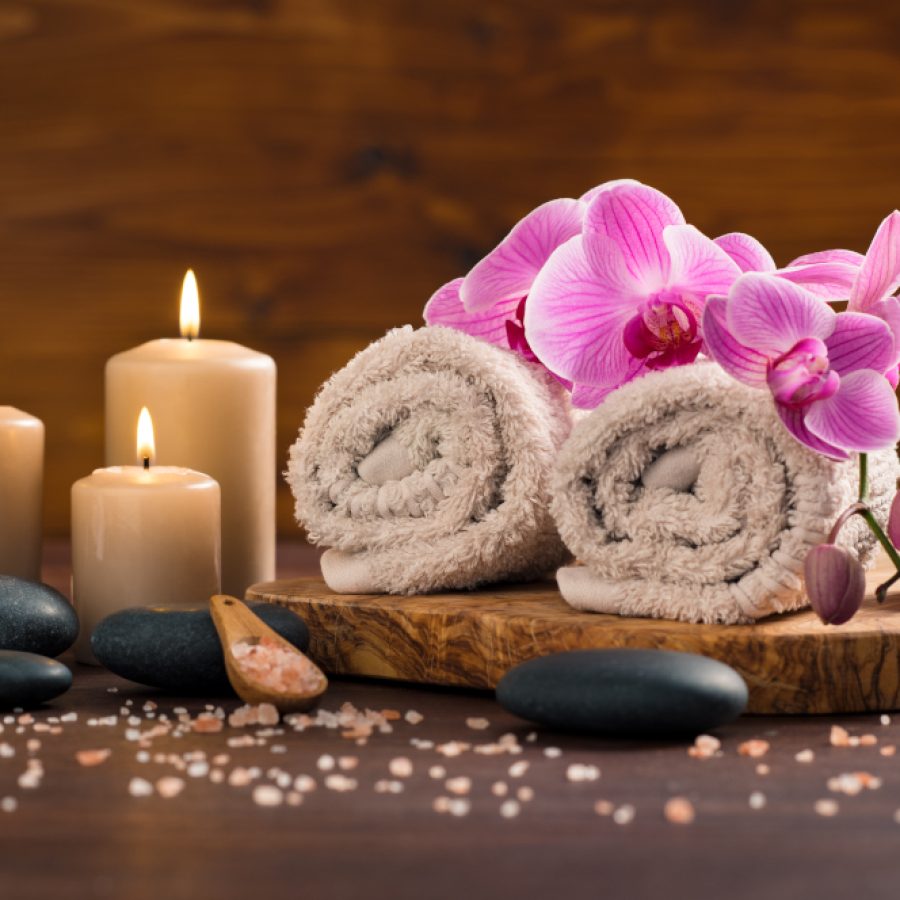 Décor de spa avec bougies allumées, serviettes et fleurs