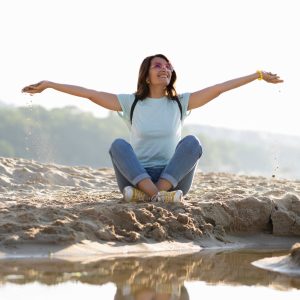 femme heureuse assise dans le sable. représentant la valeur de l'autonomie de la maison du bien-être de Margency